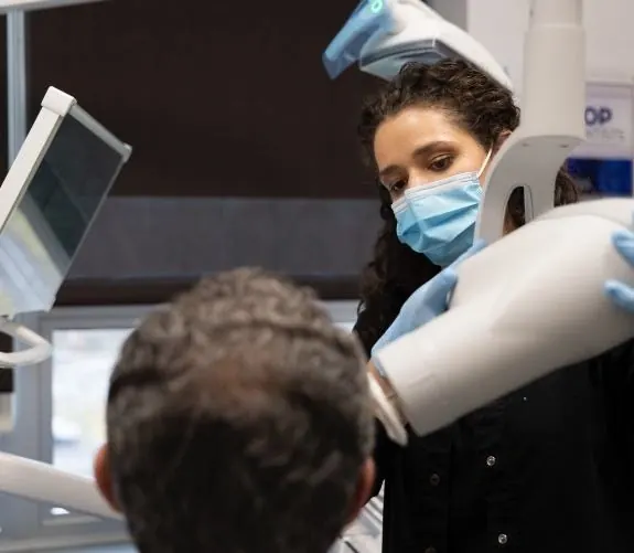 A dental assistant taking a digital scan of a patient's teeth.